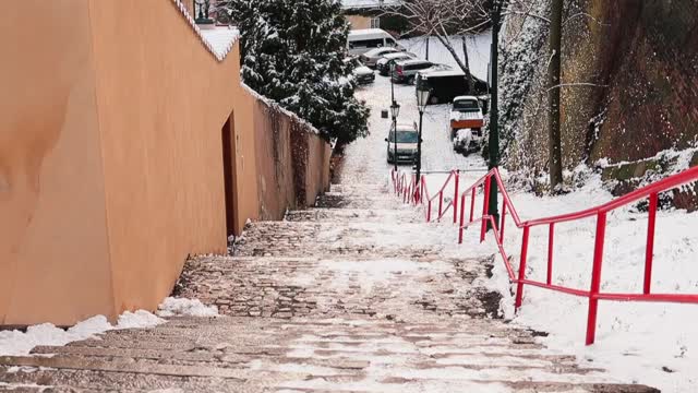 白雪覆盖的城市楼梯台阶，红色的栏杆通向下面。视频素材