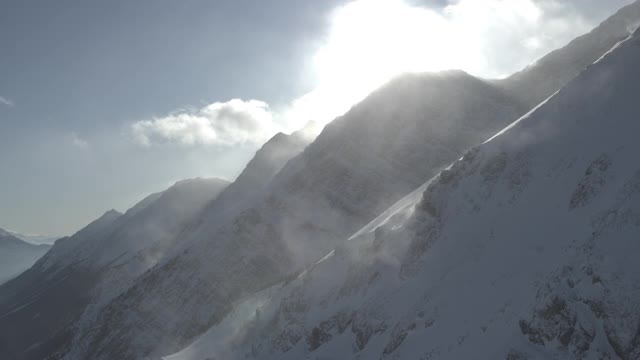 无人机在落基山脉陡峭的雪崖旁飞行视频素材