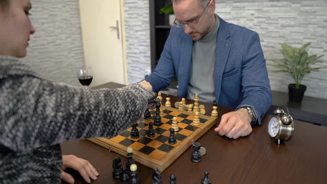 一对年轻夫妇坐在家里的桌子旁下棋视频素材