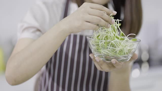 女人捧着玻璃碗，里面盛满了鲜嫩的绿色蔬菜视频素材