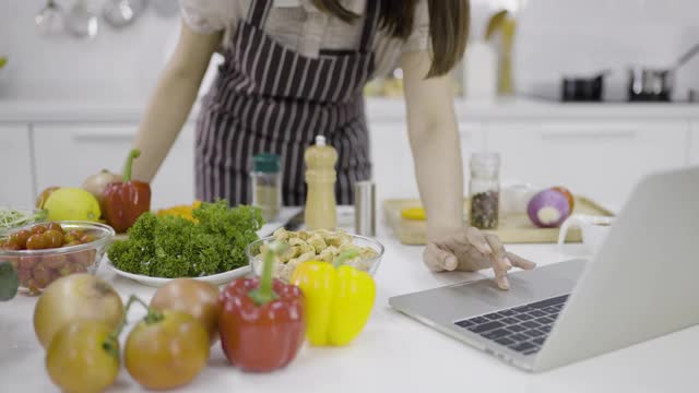 一个女人在厨房用笔记本电脑准备食物视频素材