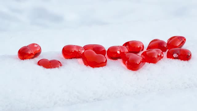 小红心玻璃上的粉状雪花在冬日里，浪漫的爱情，圣瓦伦丁节的节日概念视频素材