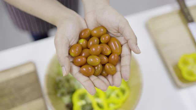 女人把整个圣女果扔进木碗里视频素材