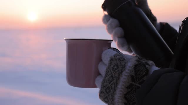 在下雪天把热水瓶里的茶倒进杯子里视频素材