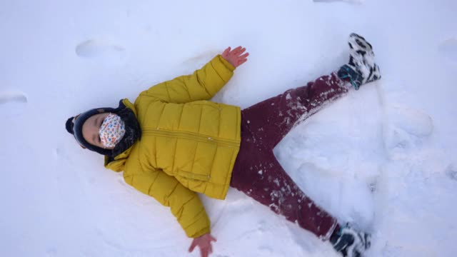 小可爱的男孩制作雪天使-播放在雪花- 4K视频视频素材