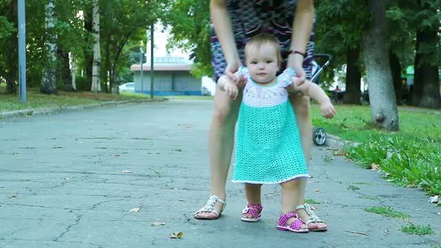 孩子的第一步。妈妈教走路，用手扶着女孩视频素材