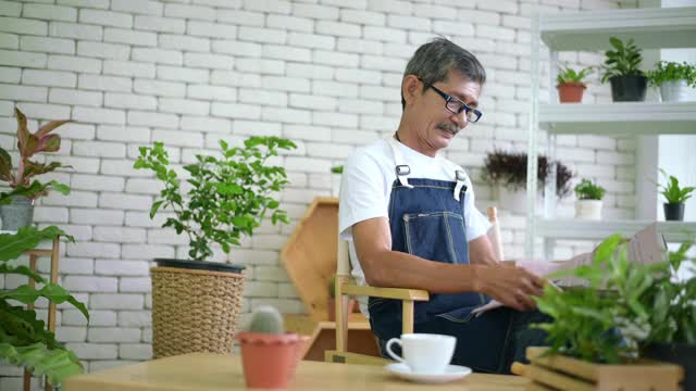 一位老人正在家中边喝咖啡边看报纸。视频素材