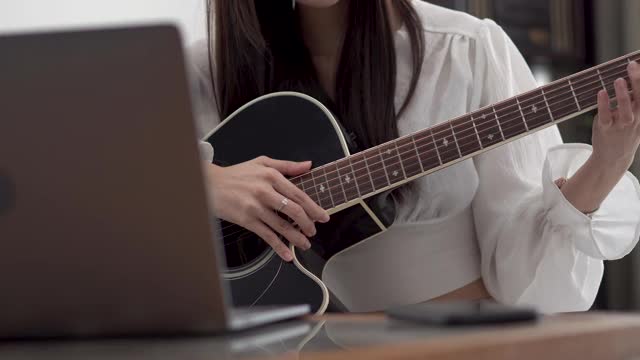 年轻女子在网上学习吉他课程。视频素材