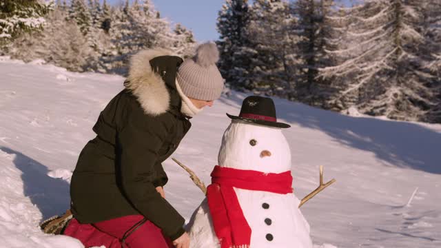 肖像:在冬天的草地上堆雪人后，快乐的女人微笑着。视频素材