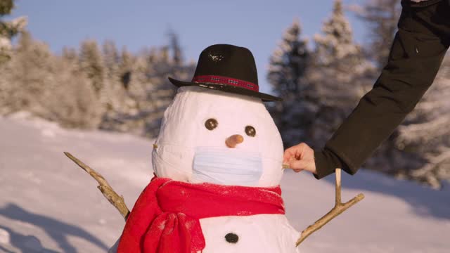 近距离观察:女游客在堆雪人时摘下了冠状病毒防护口罩。视频素材