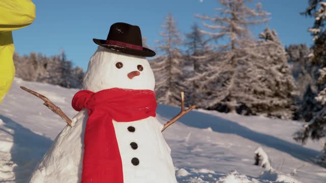 特写:不认识的人踢雪人建立在一个阳光明媚的冬日。视频素材