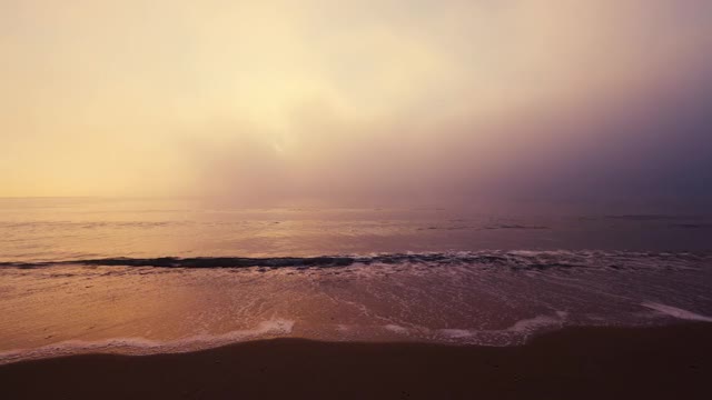 海边沙滩和雾蒙蒙的日出4k视频，海浪拍打着海沙视频素材