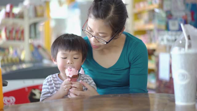 亚洲小男孩和妈妈在小店里吃冰淇淋视频素材