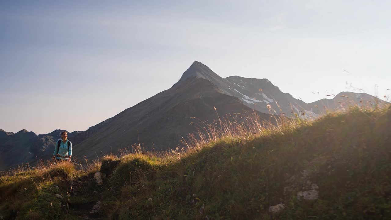 年轻的女性徒步旅行者走在山脊小径周围的山峰视频素材