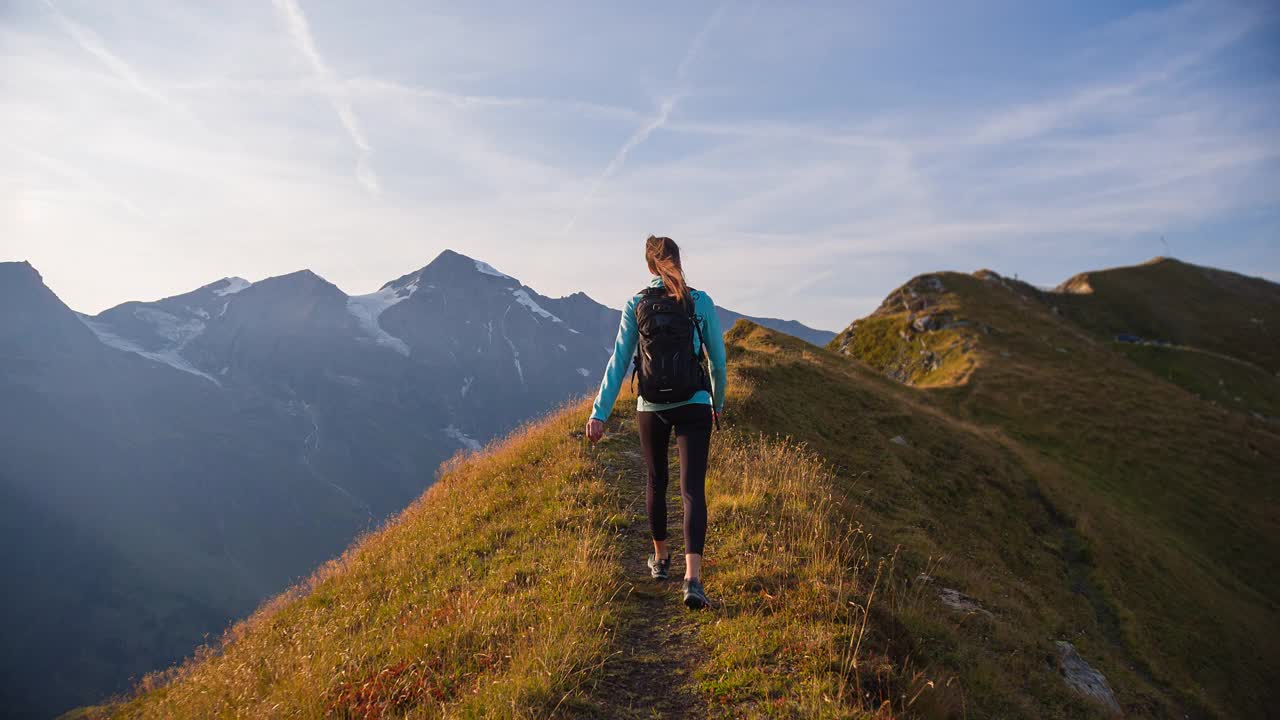 年轻的健身女士保持健康，在高山上呼吸新鲜空气，爬上山脊视频素材