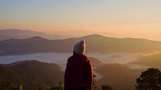 年轻女子旅行者在早晨看日出和山上的雾海，旅行的生活理念视频素材