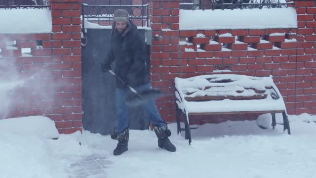 一个年轻人在郊区的房子附近除雪视频素材