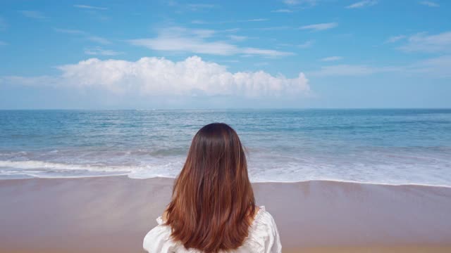 年轻女子旅行者放松和享受美丽的热带白色沙滩与海浪泡沫和透明的海，暑假和旅游概念视频素材