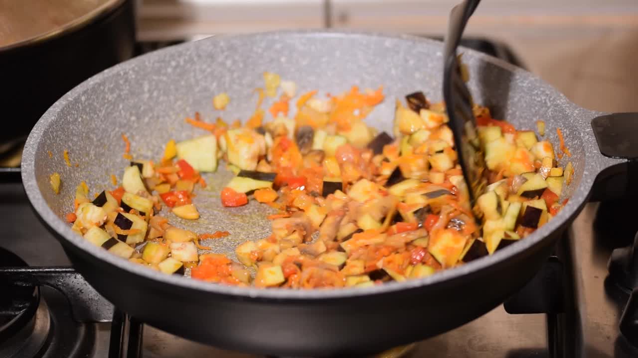 一个年轻女子在煎锅里煮蔬菜的特写镜头视频素材