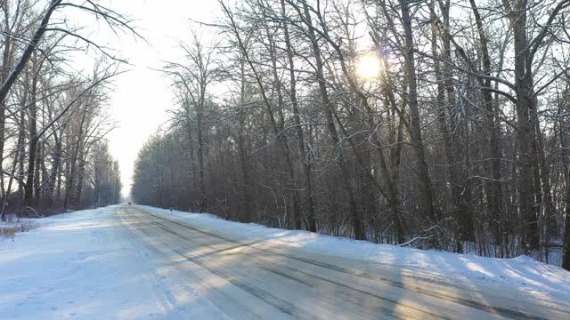 白色的汽车在冰雪覆盖的道路上快速行驶。在晴朗的日子里，越野车行驶在空旷的乡村路线上。自动移动通过风景优美的景观方式。旅行的概念。俯视图无人机拍摄视频素材