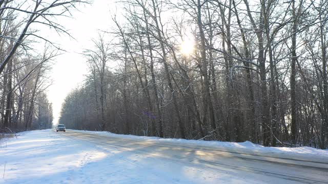 白色的汽车在冰雪覆盖的道路上快速行驶。在晴朗的日子里，越野车行驶在空旷的乡村路线上。自动移动通过风景优美的景观方式。旅行的概念。俯视图无人机拍摄视频素材