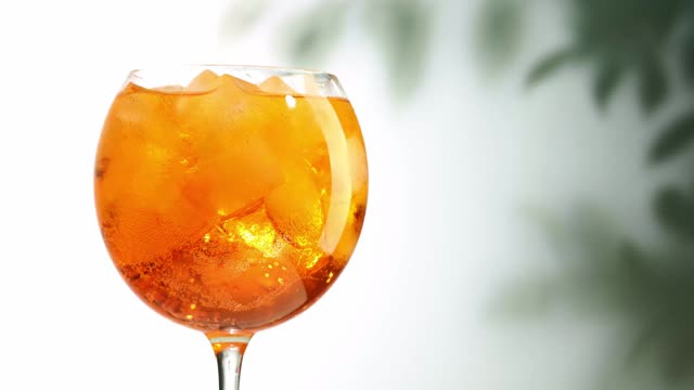 杯aperol雾化鸡尾酒与冰打开散焦树叶背景放大视频素材