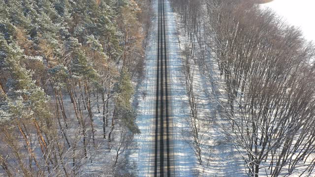 航拍白色越野车行驶在积雪覆盖的森林道路上。在冬天，汽车在结冰的森林路线上行驶。自动驾驶越过美丽的自然之路。旅行和周末活动的概念。以上观点视频素材