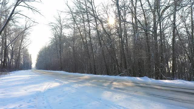 白色的汽车在冰雪覆盖的道路上快速行驶。在晴朗的日子里，越野车行驶在空旷的乡村路线上。自动移动通过风景优美的景观方式。旅行的概念。俯视图无人机拍摄视频素材