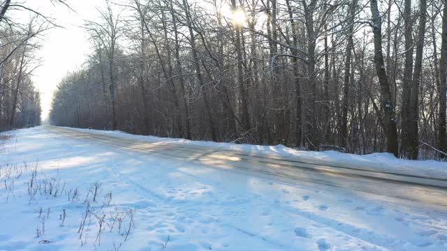 白色的汽车在冰雪覆盖的道路上快速行驶。在晴朗的日子里，越野车行驶在空旷的乡村路线上。自动移动通过风景优美的景观方式。旅行的概念。俯视图无人机拍摄视频素材