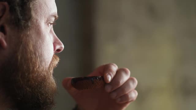 一幅留着胡子的嬉皮士男子用陶碗喝中国茶的肖像。中国茶道视频素材