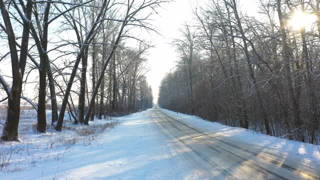 白色的汽车在冰雪覆盖的道路上快速行驶。在晴朗的日子里，越野车行驶在空旷的乡村路线上。自动移动通过风景优美的景观方式。旅行的概念。俯视图无人机拍摄视频素材