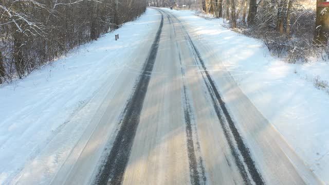 白色的汽车在冰雪覆盖的道路上快速行驶。在晴朗的日子里，越野车行驶在空旷的乡村路线上。自动移动通过风景优美的景观方式。旅行的概念。俯视图无人机拍摄视频素材