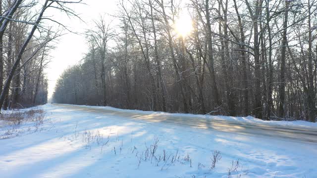 白色的汽车在冰雪覆盖的道路上快速行驶。在晴朗的日子里，越野车行驶在空旷的乡村路线上。自动移动通过风景优美的景观方式。旅行的概念。俯视图无人机拍摄视频素材