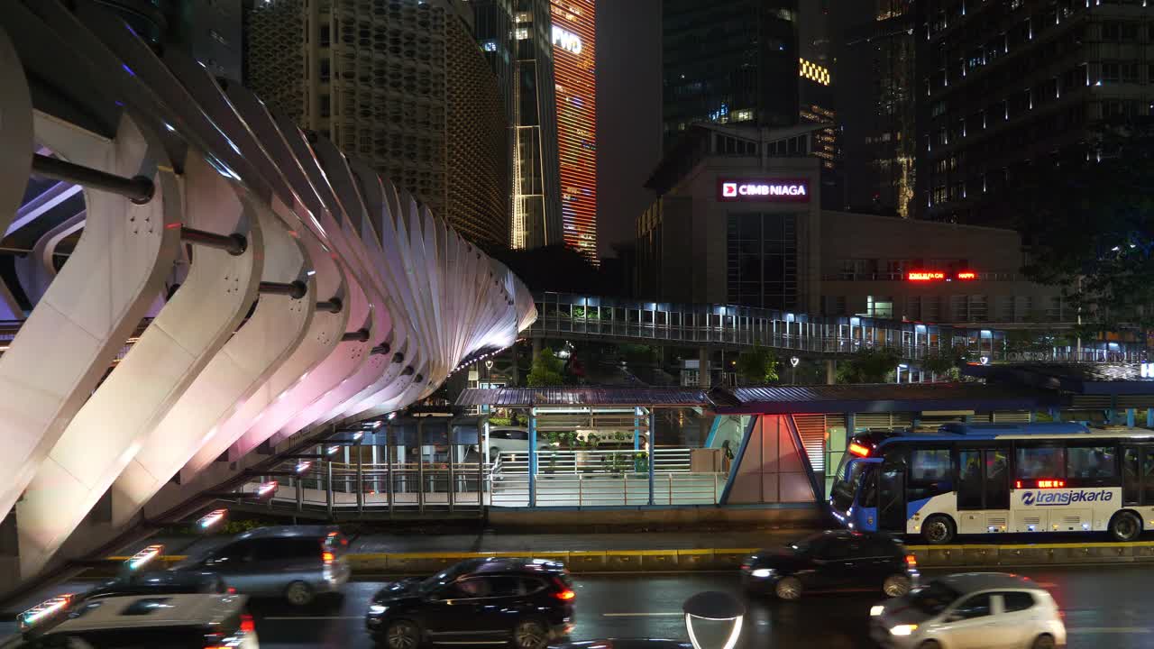 夜光雅加达市区著名的现代步行桥交通街道顶部4k全景印尼视频素材