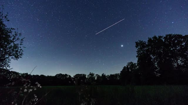 在夜晚的天空中移动的银河与树木的剪影乡村景观视频素材