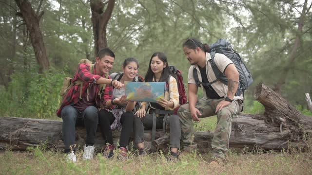 徒步旅行和露营概念。四名亚洲男女徒步旅行者正在用地图计划他们的丛林之旅。视频素材