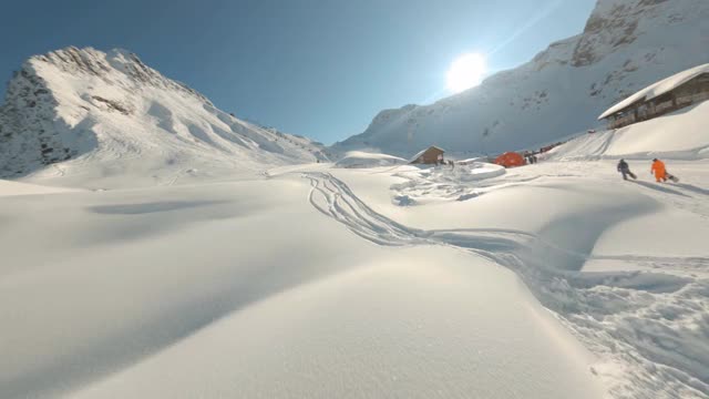 在阳光明媚的冬日，无人机在雪山度假村上空飞行，靠近缆车。滑雪胜地的雪坡。雪山下坡旅游运输用索道。从fpv运动无人机空中拍摄视频素材