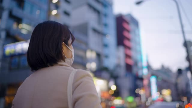 晚上在城市街道上行走的妇女用保护性面罩遮住脸视频素材