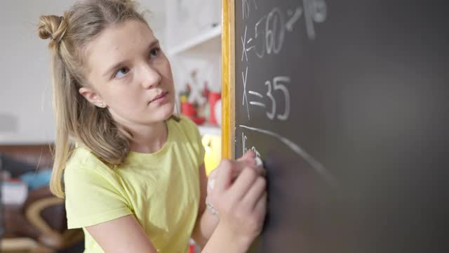 一个天才白人女孩在学校的黑板上解数学题。聪明聪明的女学生在室内学习数学。Z一代的教育和智力。视频素材