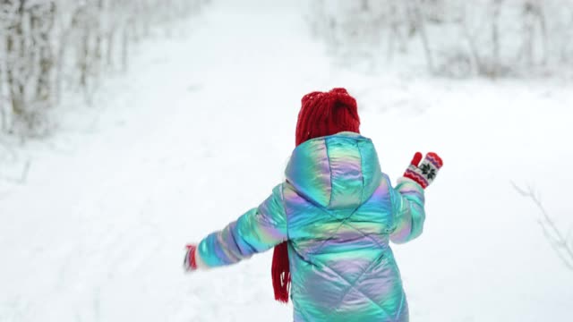 小朋友在冬天在雪地里玩到公园外面。孩子用冷杉摇落雪花。冬天的幸福观。下雪的天气视频素材