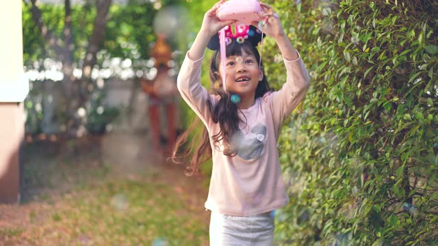 小女孩在家里的花园里玩泡泡视频素材