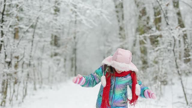 可爱的小女孩在温暖的冬天的雪天户外。快乐的小女孩在冬天玩雪。女孩喜欢冬天，有霜冻的日子视频素材