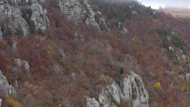 从无人机上俯瞰山顶的森林。从无人机空中向后看景观岩石悬崖和山上覆盖着树木在雾霾云。鬼谷德默尔吉，4k视频素材