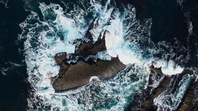 海浪拍打在岩石上的电影空中俯视图。视频素材