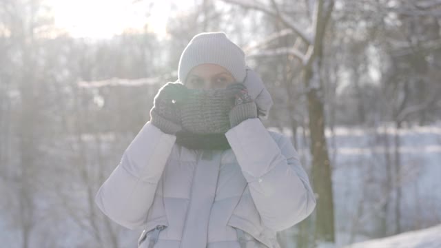 在寒冷的日子里，孕妇穿着暖和的夹克，带着兜帽，走在下雪的公园里视频素材