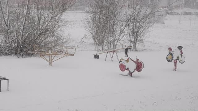 冬天的雪落在欧洲城市的一条街上。降雪气旋。城市的冬天，暴风雪。汽车和住宅建筑背景下的暴风雪。空旷的操场上覆盖着雪。视频素材