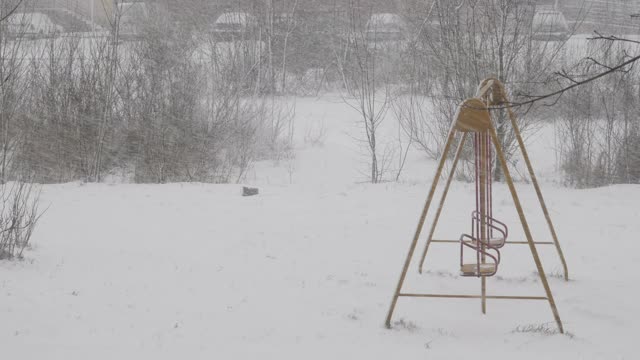 冬天的雪落在欧洲城市的一条街上。降雪气旋。城市的冬天，暴风雪。汽车和住宅建筑背景下的暴风雪。空旷的操场上覆盖着雪。视频素材