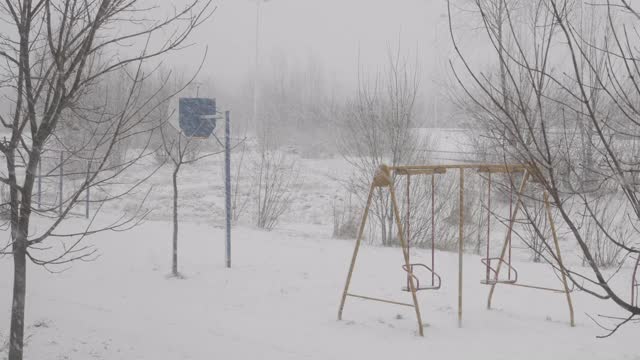 冬天的雪落在欧洲城市的一条街上。降雪气旋。城市的冬天，暴风雪。汽车和住宅建筑背景下的暴风雪。空旷的操场上覆盖着雪。视频素材