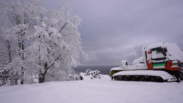 滑雪胜地用的除雪设备。新冠肺炎一级防范禁闭期间，一辆被积雪覆盖的拖拉机停在那里。波兰，Zieleniec, Duszniki-Zdroj, 2021年1月10日视频素材