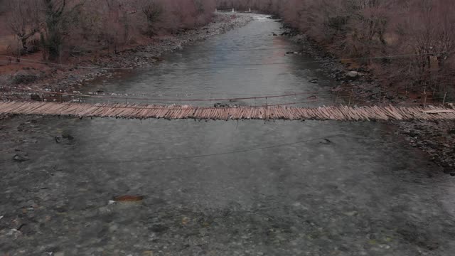 一座古老的悬索桥横跨山间河流，俯瞰一座废弃的桥，d- cinlike，没有颜色分级视频素材